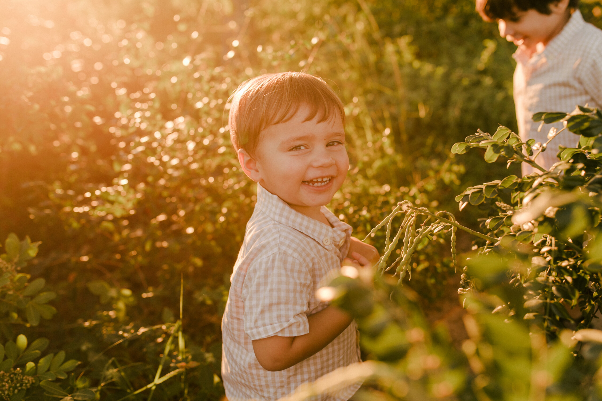 um menino está sorrindo para a câmera, enquanto a luz do sol dourada reflete em seu rosto